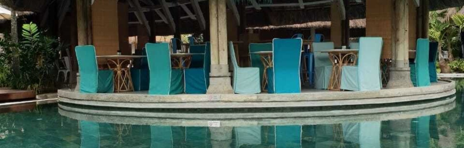 A poolside area with a thatched-roof structure, lounge chairs, and a book titled 'MARC LEVY'.