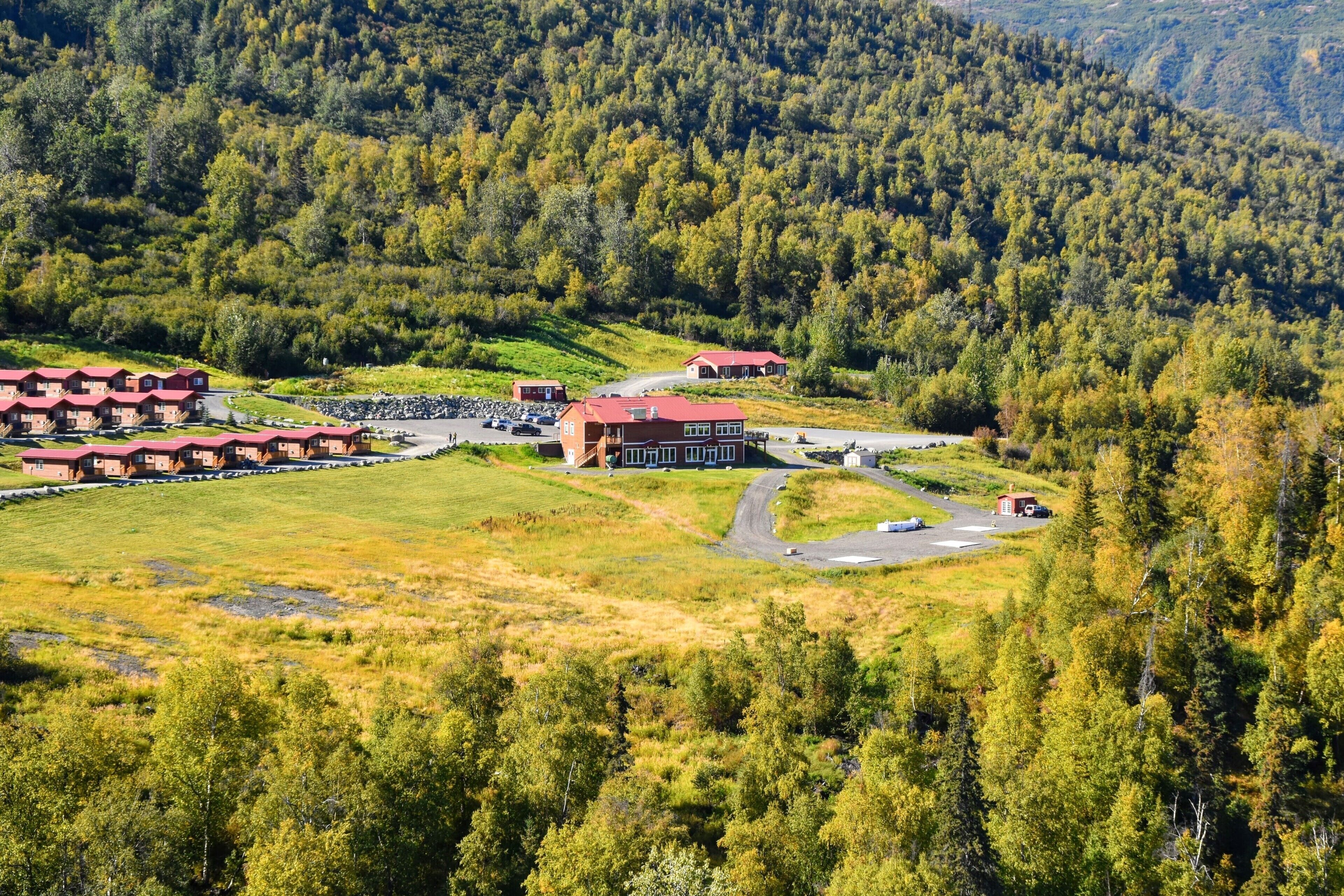 A lodge with red roofs surrounded by forested hills.