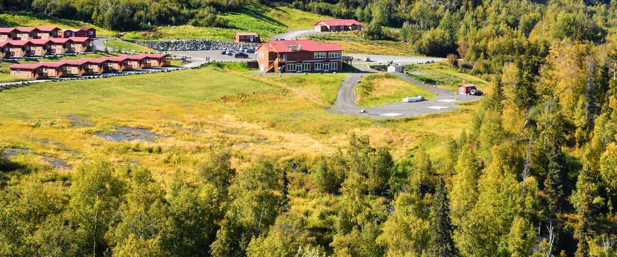 A lodge with red roofs surrounded by forested hills.