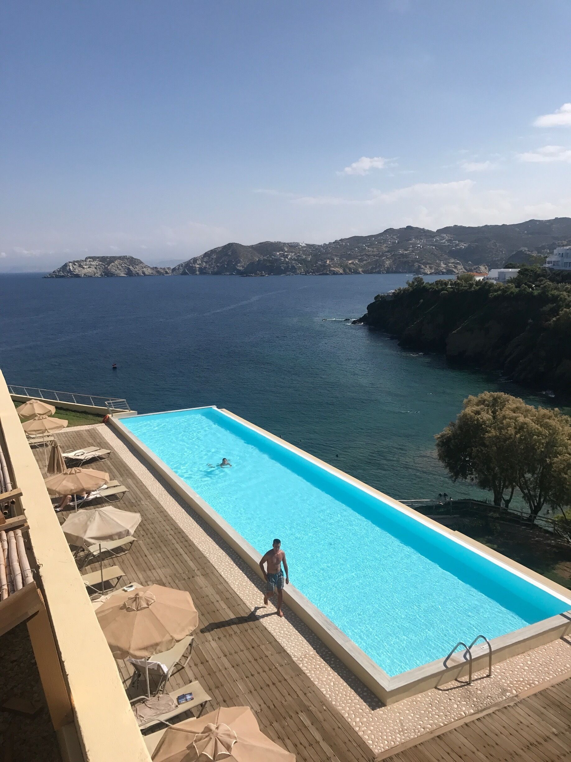 A swimming pool with a view of the sea and distant hills.