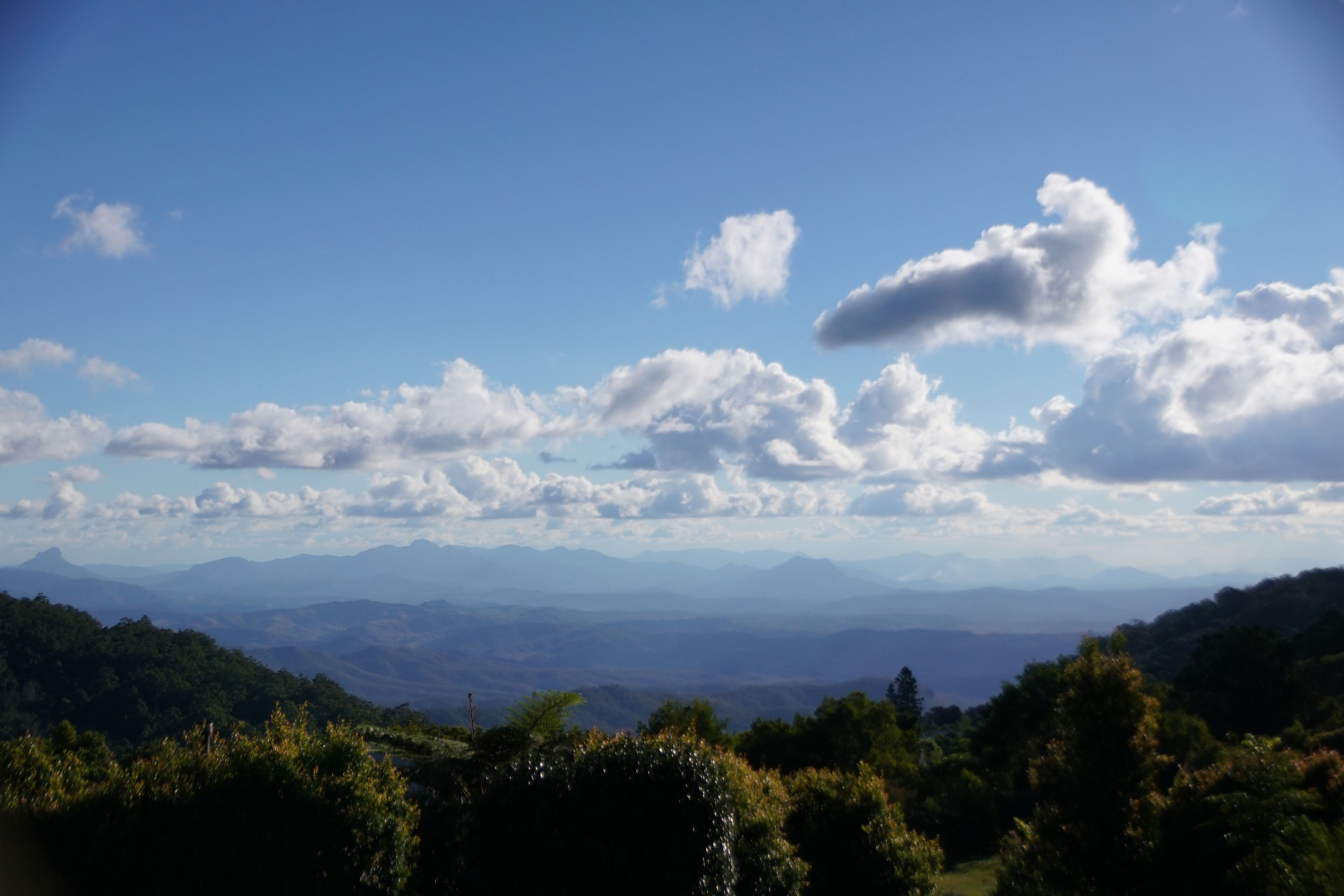 A mountainous landscape with a clear blue sky and scattered clouds.