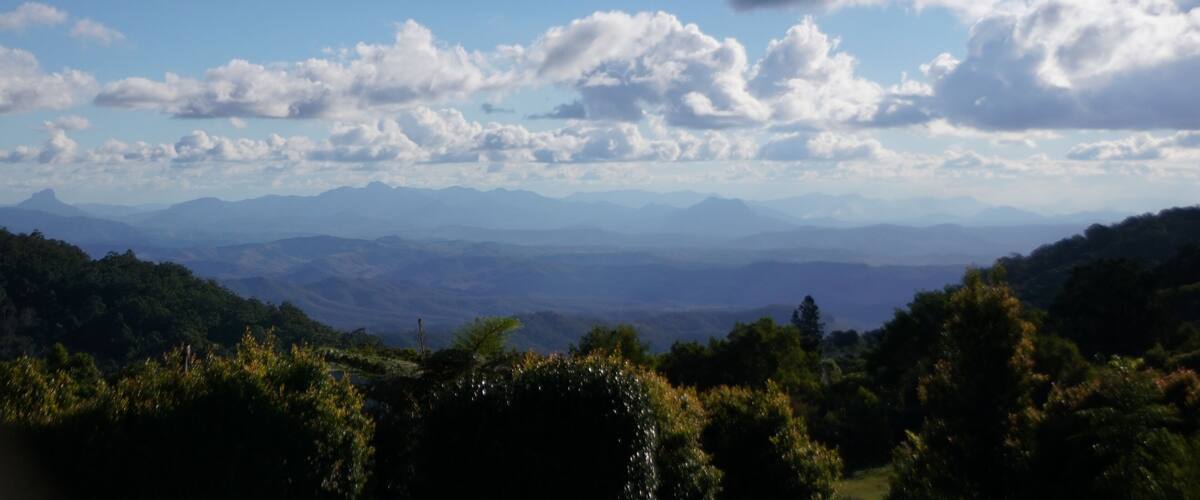 A mountainous landscape with a clear blue sky and scattered clouds.