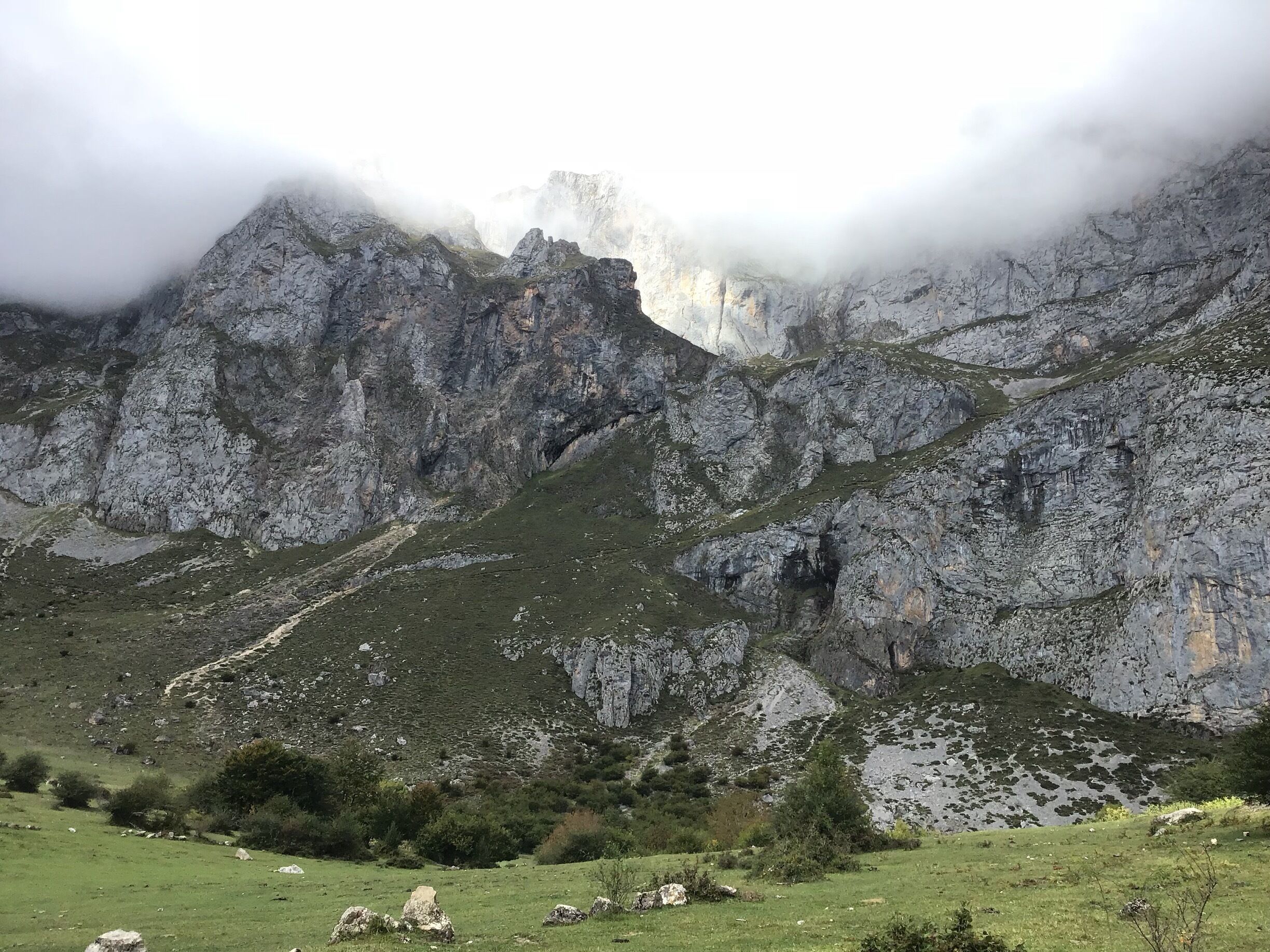 A mountainous landscape with rocky cliffs and patches of green vegetation.