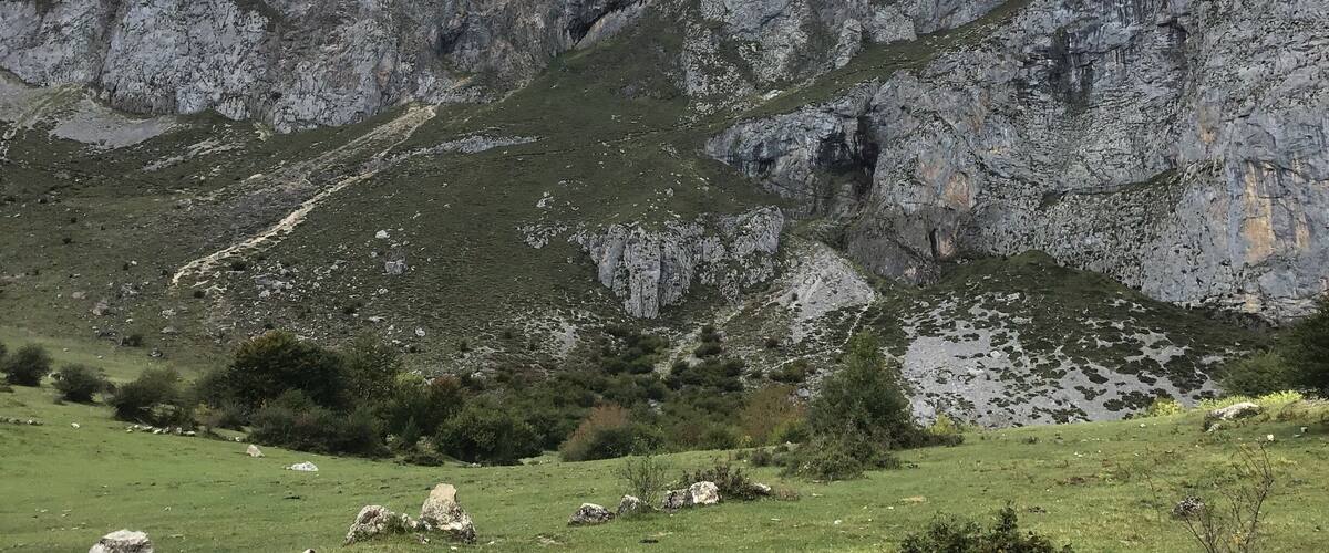 A mountainous landscape with rocky cliffs and patches of green vegetation.