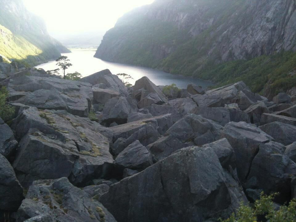 A rocky landscape with large boulders and a calm body of water in the distance.