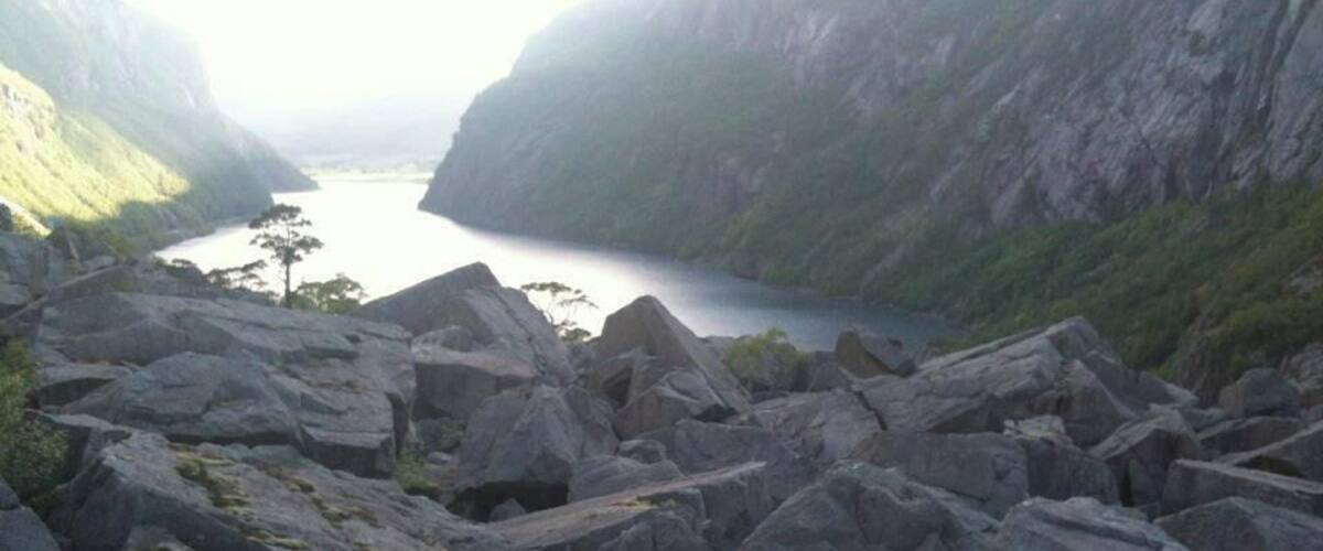 A rocky landscape with large boulders and a calm body of water in the distance.