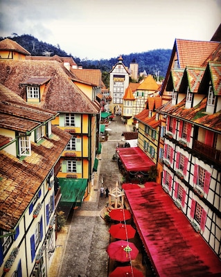 Una calle estrecha con edificios coloridos, una fuente en el centro y una montaña al fondo.