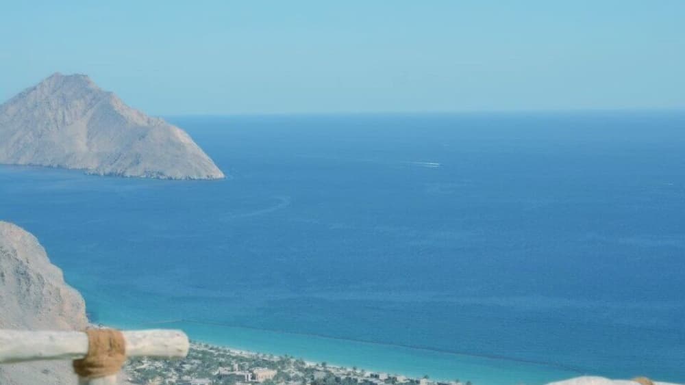 Un paysage côtier avec une montagne imposante et une petite ville au bord de la mer.