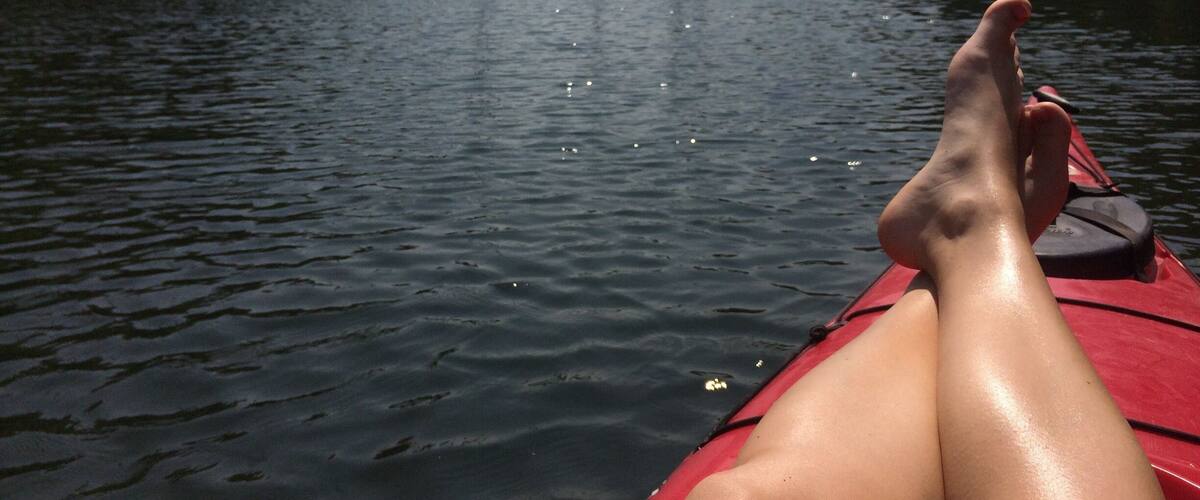 A calm river with a red kayak, surrounded by forested banks.