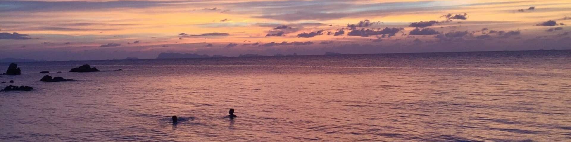 A beach at sunset with a clear sky and calm sea.