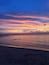 Une plage au coucher du soleil, avec un ciel dégagé et une mer calme.