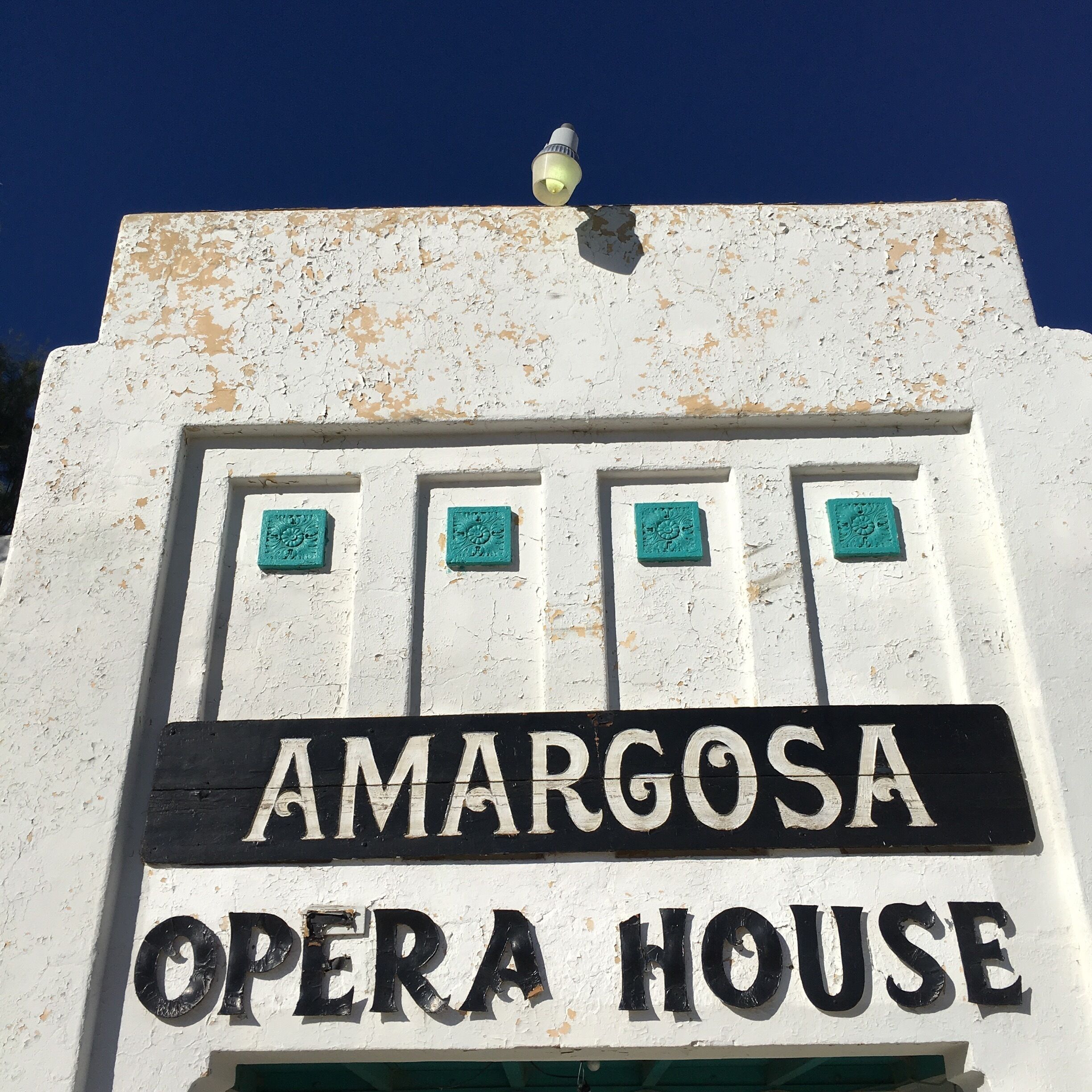 A sign for Amargosa Opera House with decorative tiles above it.