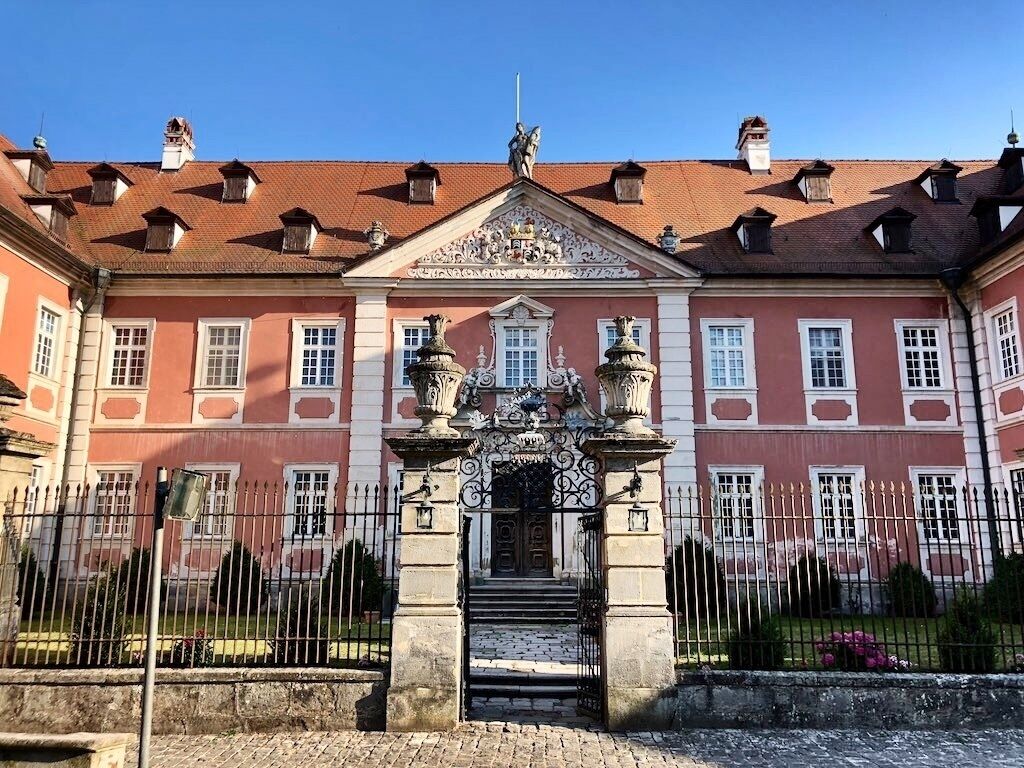 Hotel Schloss Reichmannsdorf is on the site of a Truchsess castle destroyed by fire in 1642, Johann Dientzenhofer built between 1714 and 1719 according to plans of his brother Leonhard for Wolf Philipp von Schrottenberg a castle as a three-wing complex above an artificial lake, with a richly decorated display side, high, mansard-divided roof and a mighty coat of arms gable. The stuccoes in the staircase are by Johann Christian Beuntner, the paintings by Johann Jakob Gebhard. The castle still belongs to the von Schrottenberg family and has been a hotel since 2011.