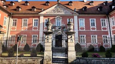 Ein historisches Gebäude mit roter Fassade, aufwendigem Eingang und einem Ziegeldach.