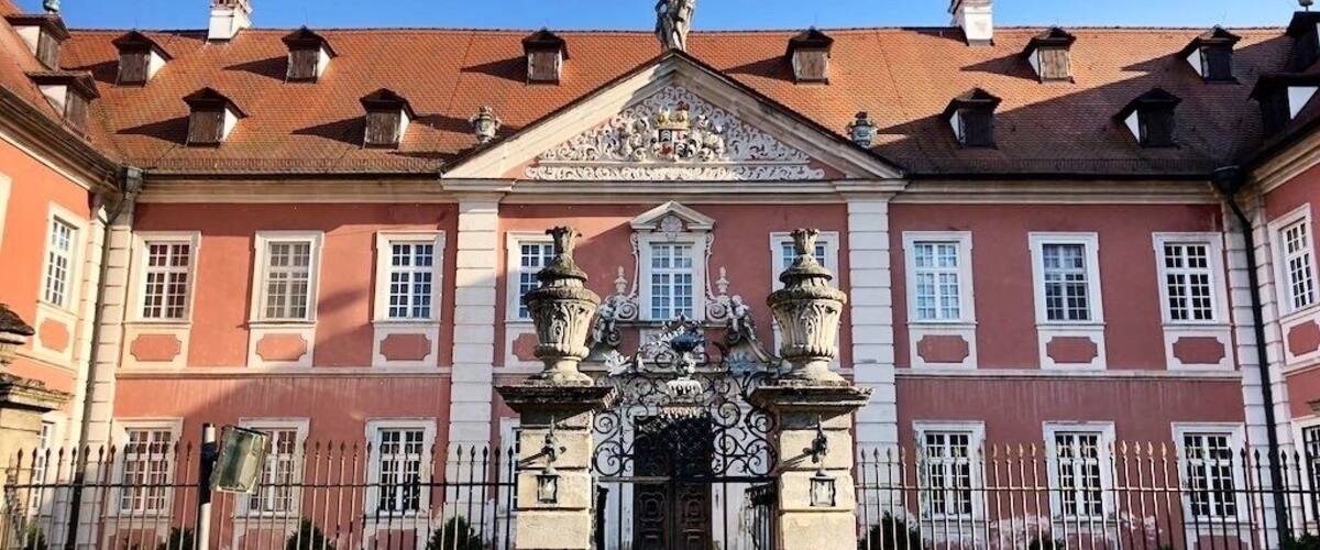 A historic building with a red facade, ornate entrance, and a tiled roof.