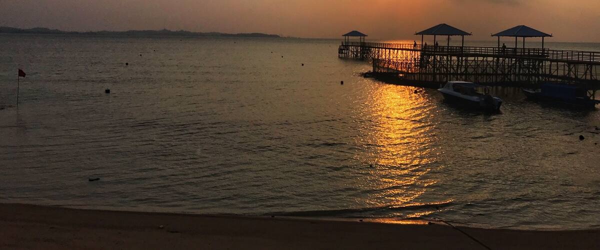 A pier extending into calm waters at sunset.