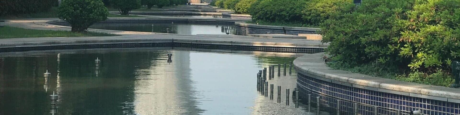 A modern architectural structure with a circular design, surrounded by a water body and greenery.