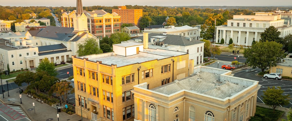 A cityscape with a prominent church steeple, a courthouse, and various buildings.
