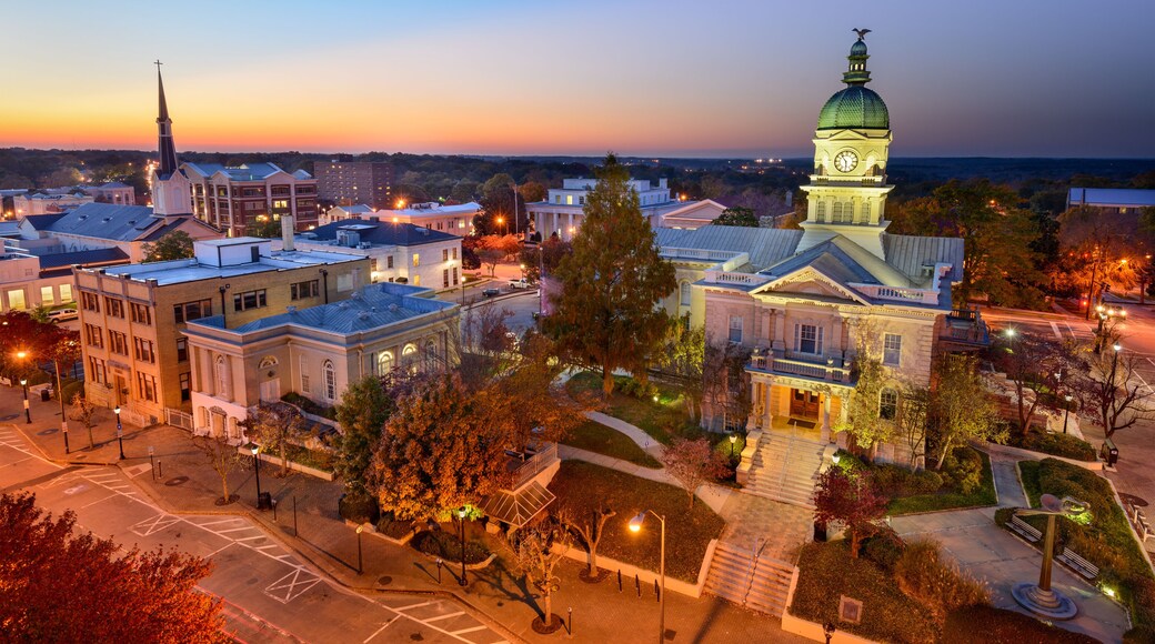 A cityscape at dusk with illuminated buildings, a prominent church steeple, and a clock tower.