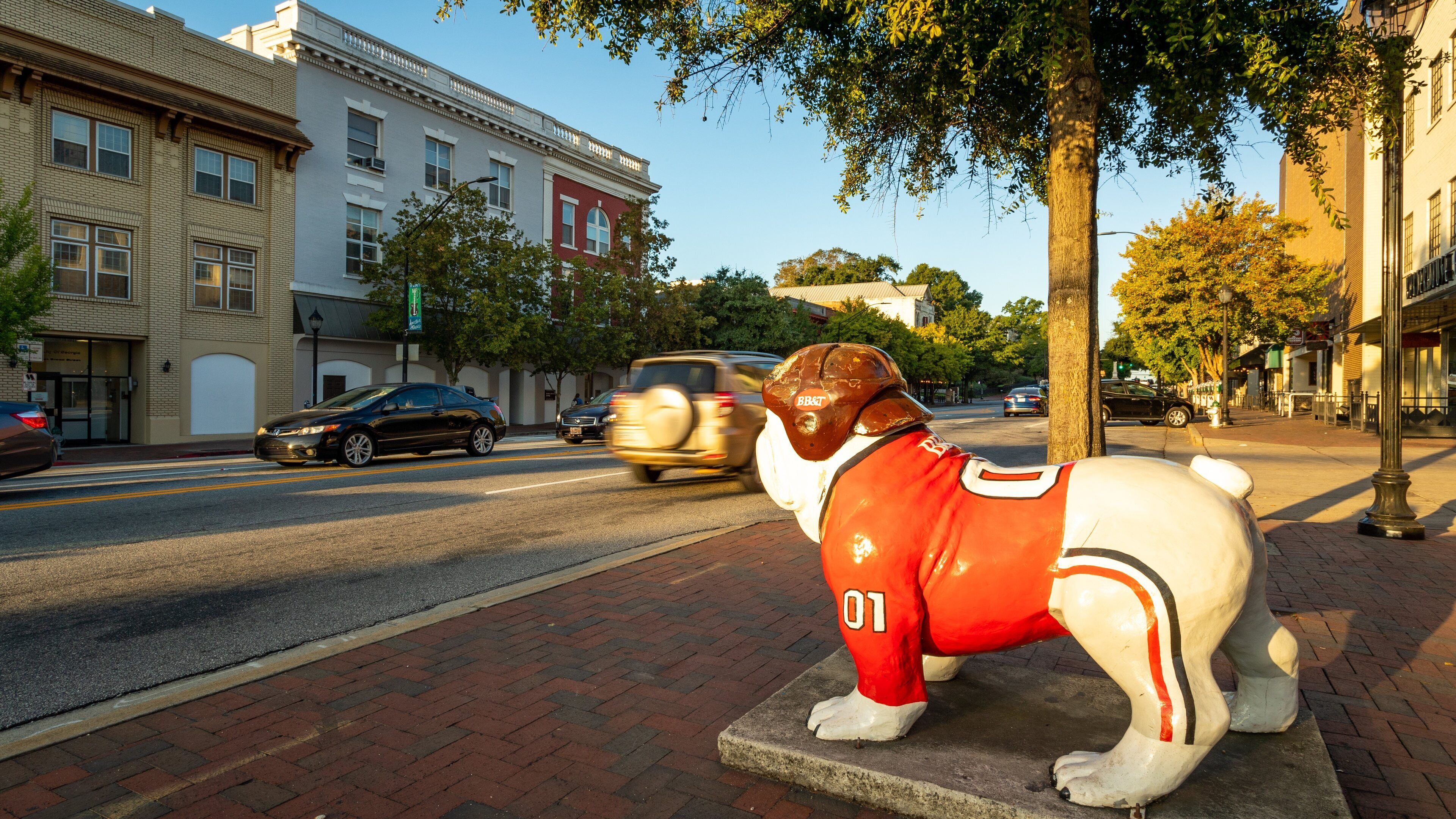 A bull statue wearing a red jersey with the number 01 on a sidewalk.