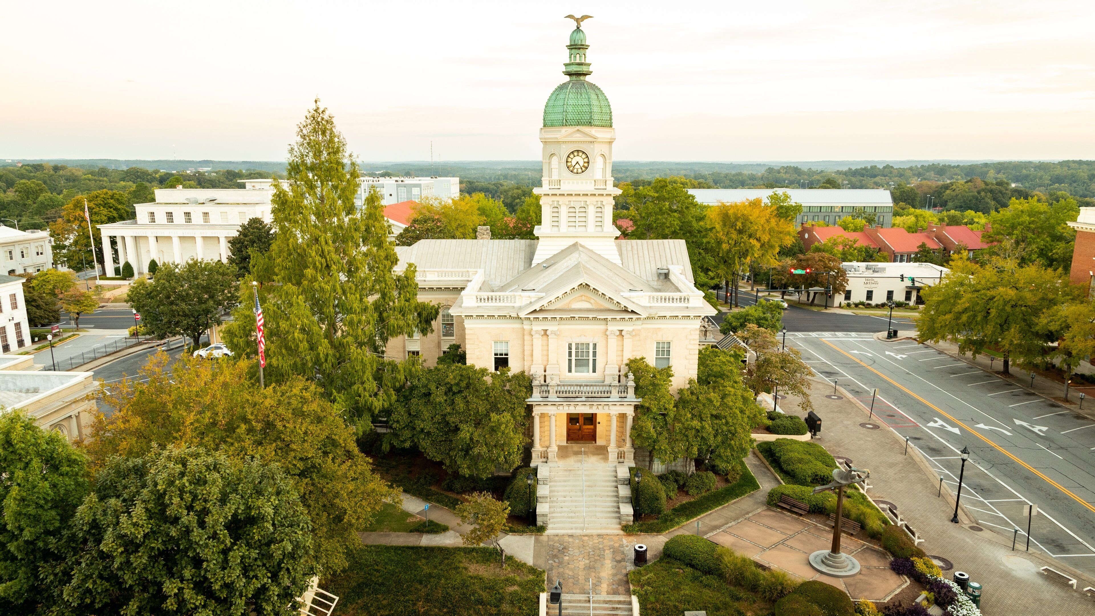 A historic building with a clock tower, surrounded by trees and a city street.