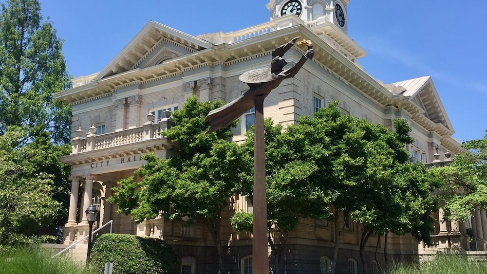 Un bâtiment historique doté d’une tour horlogée et d’une statue devant l’entrée.