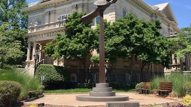 A historic building with a clock tower and a statue in front.