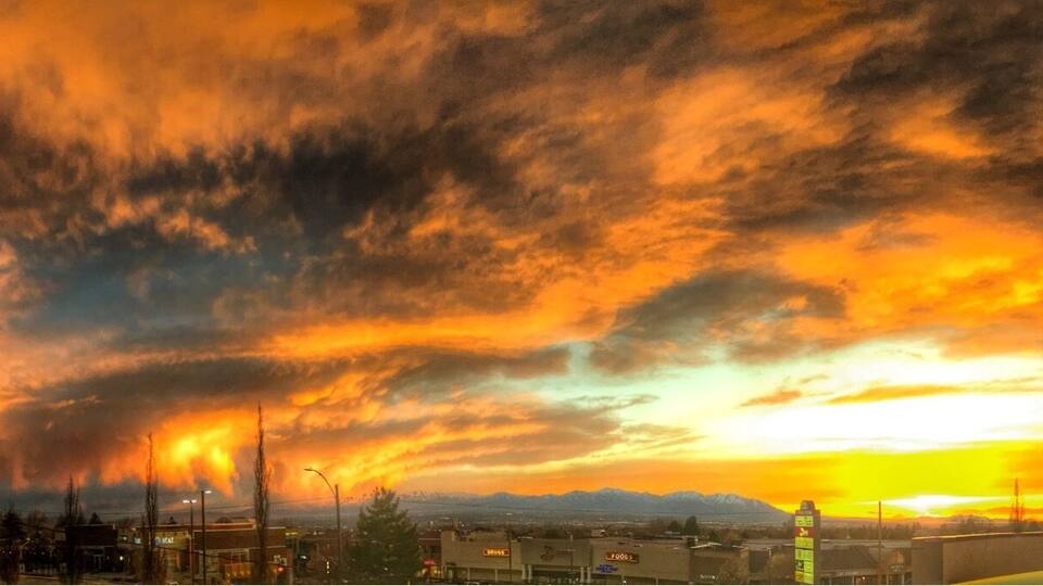 Un atardecer sobre una ciudad con montañas al fondo.