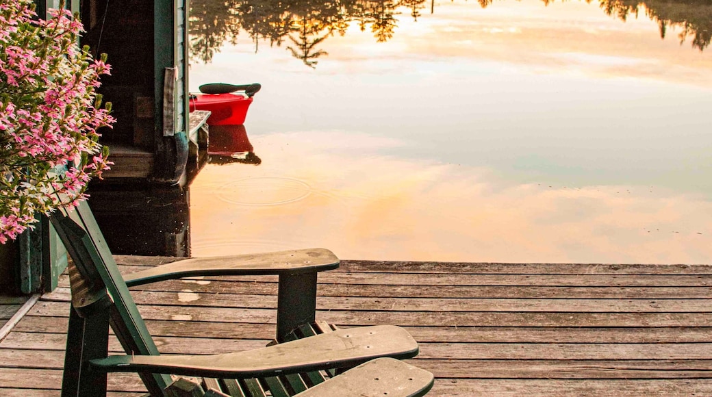 USA, New York. Adirondack Park, Saranac Lake, Hoel Pond, Adirondack chairs on boathouse dock.