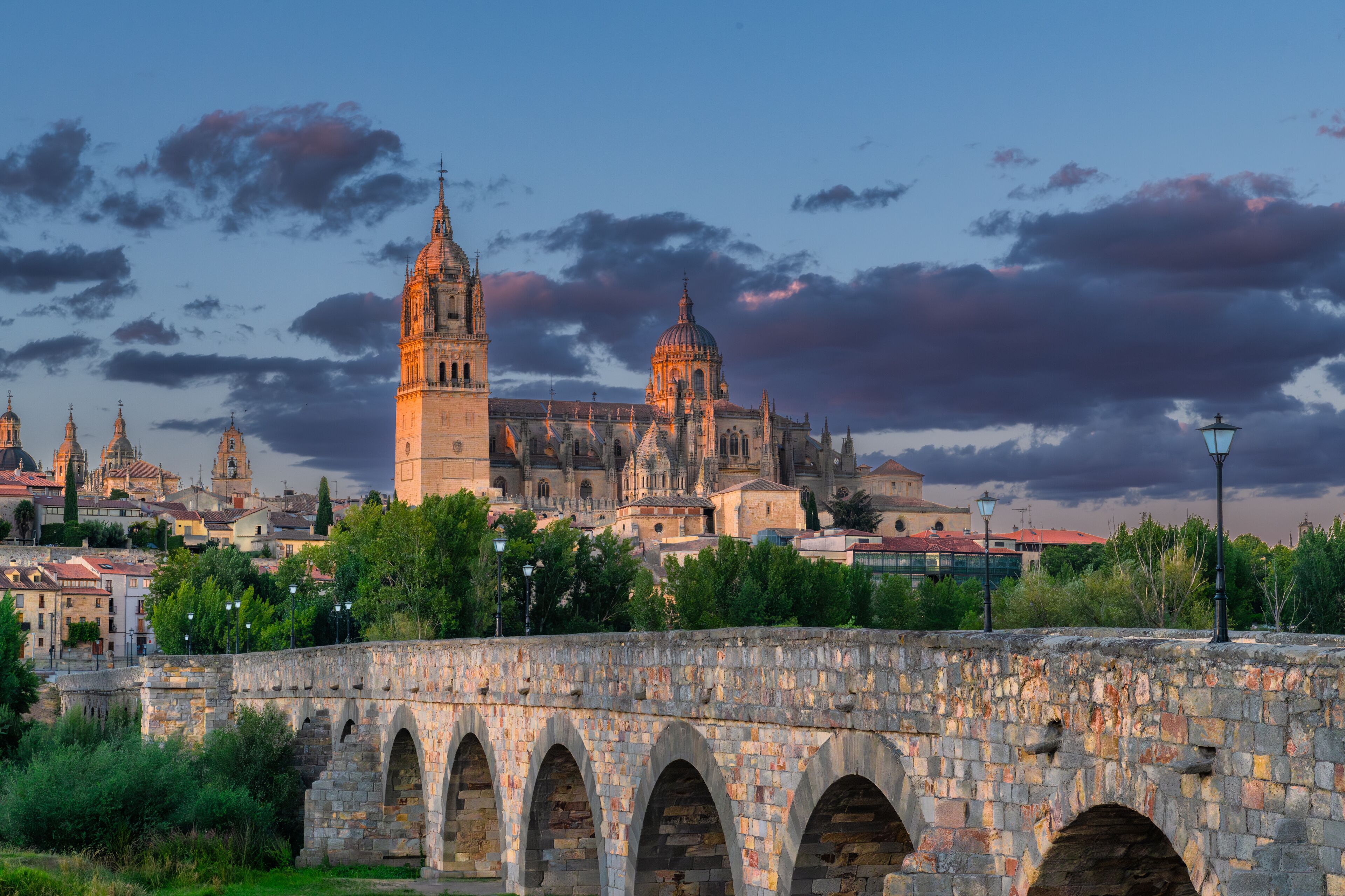 Sunset view of The Salamanca Roman Bridge (Puente Romano de Salamanca, Puente Mayor del Tormes), ancient stone structure over the Tormes River with Salamanca Cathedral in the background