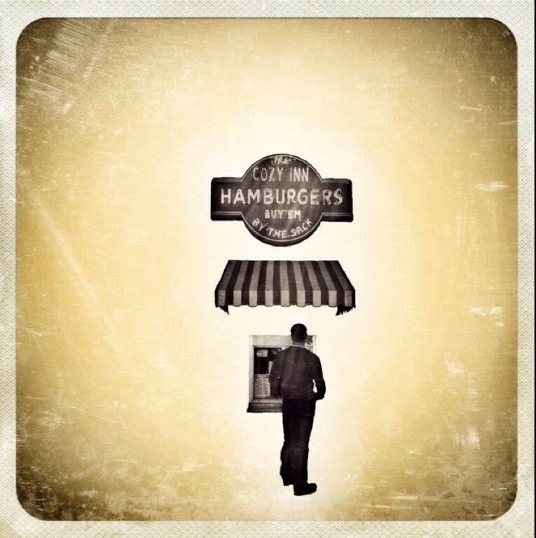"I Can Smell Ya From Here"

This is The Cozy Inn, Salina's pride & joy. This little Kansas burger stand has been sitting here for over 89 years. The business first started when White Castle was introduced to Wichita, KS back in 1921. The owner at the time decided to jump on the coat tails of White Castle's success, and open up a stand featuring little hamburgers as well. He decided to keep it simple. Little patty, little bun, a pickle, little bit of mustard & ketchup, and oh yeah, a mountain of grilled onions. These onions are the reason why people keep coming back here. You can smell the onions from blocks away. The restaurant itself, only has 6 barstools directly next to the legendary grill. So if you sit inside, everyone in town knows what you had for lunch that day. No joke at all. It will permeate your clothes. It's not a bad thing, unless you hate the smell of onions.

While I was standing in line, waiting for my combo meal of 6 sliders, a bag of chips, and a can of soda; a gentleman shared with me the little known history of The Cozy. He told me that some years back, some new owners came in and tossed the grill that had been with The Cozy since its opening. They threw it in the landfill and replaced it with a brand new one. The people of Salina were not impressed with the new taste of The Cozy's burgers. Business plummeted apparently. And like Superman has so famously done in the comic books, the old owner came back just in the nick of time and bought back his beloved hamburger stand, and saved the business from going under. His first decision? Get rid of this new grill, and go find his old one in the landfill. Once the old grill was back up and running, the business returned.

I don't know what it is about this place, but I instantly fell in love. It inhabits everything you want out of a small town hamburger stand. The smells, the atmosphere, the outdoor seating on a sidewalk, and of course, the phenomenal taste of these little burgers. My favorite part? They don't even wrap up the burgers. They just stack the 6 burgers in a paper sack. And if you're thinking 6 is too many? Too bad. That's the smallest amount that they sell.

For a complete experience of The Cozy, come to Salina. If you don't want to make the trip, you can watch the episode of "Diners, Drive-Ins, & Dives" that featured this amazing little hamburger stand located in the heart of America, Kansas.
