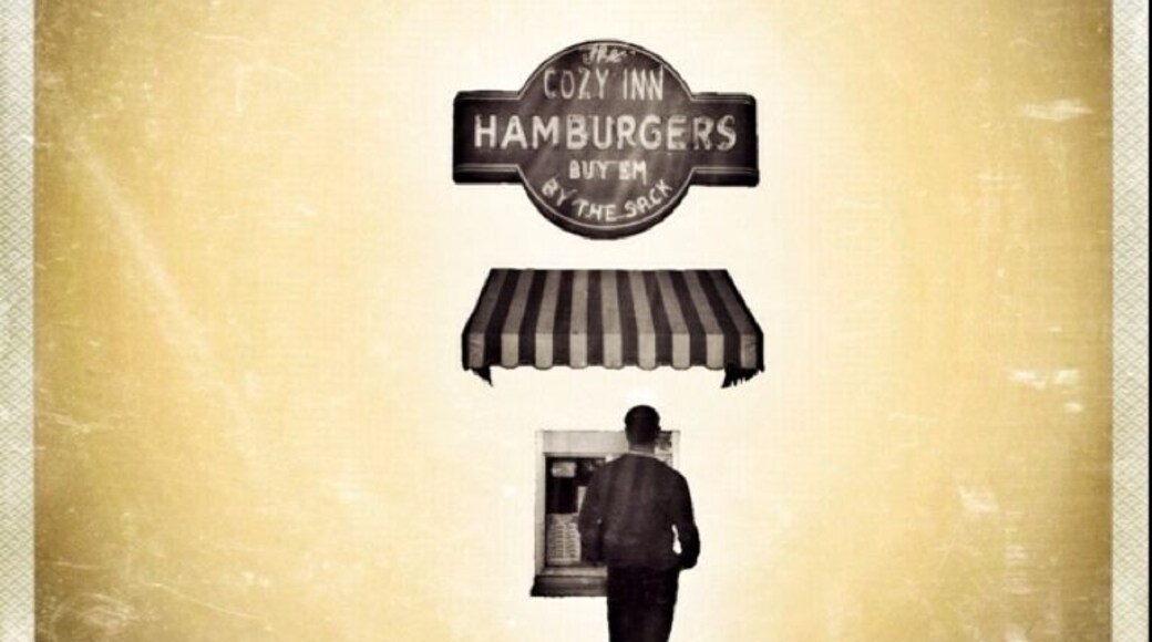 "I Can Smell Ya From Here"
This is The Cozy Inn, Salina's pride & joy. This little Kansas burger stand has been sitting here for over 89 years. The business first started when White Castle was introduced to Wichita, KS back in 1921. The owner at the time decided to jump on the coat tails of White Castle's success, and open up a stand featuring little hamburgers as well. He decided to keep it simple. Little patty, little bun, a pickle, little bit of mustard & ketchup, and oh yeah, a mountain of grilled onions. These onions are the reason why people keep coming back here. You can smell the onions from blocks away. The restaurant itself, only has 6 barstools directly next to the legendary grill. So if you sit inside, everyone in town knows what you had for lunch that day. No joke at all. It will permeate your clothes. It's not a bad thing, unless you hate the smell of onions.
While I was standing in line, waiting for my combo meal of 6 sliders, a bag of chips, and a can of soda; a gentleman shared with me the little known history of The Cozy. He told me that some years back, some new owners came in and tossed the grill that had been with The Cozy since its opening. They threw it in the landfill and replaced it with a brand new one. The people of Salina were not impressed with the new taste of The Cozy's burgers. Business plummeted apparently. And like Superman has so famously done in the comic books, the old owner came back just in the nick of time and bought back his beloved hamburger stand, and saved the business from going under. His first decision? Get rid of this new grill, and go find his old one in the landfill. Once the old grill was back up and running, the business returned.
I don't know what it is about this place, but I instantly fell in love. It inhabits everything you want out of a small town hamburger stand. The smells, the atmosphere, the outdoor seating on a sidewalk, and of course, the phenomenal taste of these little burgers. My favorite part? They don't even wrap up the burgers. They just stack the 6 burgers in a paper sack. And if you're thinking 6 is too many? Too bad. That's the smallest amount that they sell.
For a complete experience of The Cozy, come to Salina. If you don't want to make the trip, you can watch the episode of "Diners, Drive-Ins, & Dives" that featured this amazing little hamburger stand located in the heart of America, Kansas.