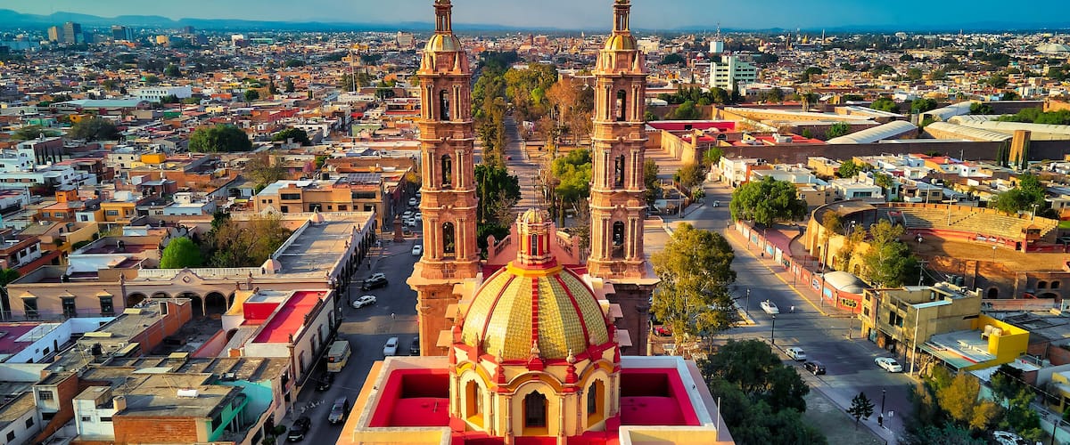 A cityscape with a prominent church featuring a large golden dome and two bell towers.