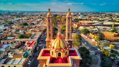 Un paisaje urbano con una iglesia destacada que presenta una cúpula dorada grande y dos torres de campanas.