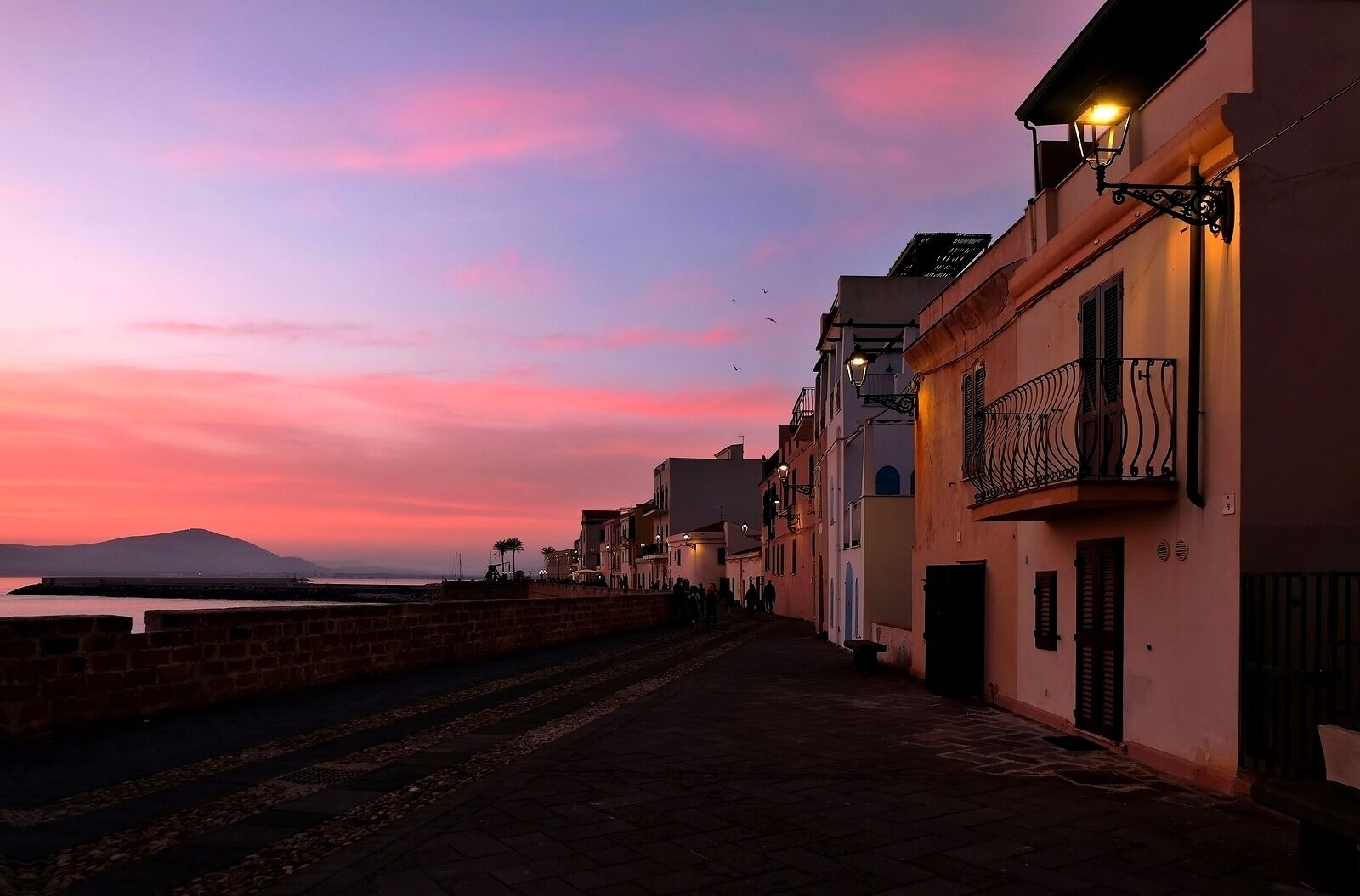 Bastioni Marco Polo in Alghero ( west coast of Sardinia , Italy ) is where tourists and locals go for a stroll anytime of day but sunset time is justifiably prime time to come watch the sun slowly sinking into the sea#On the Road . .