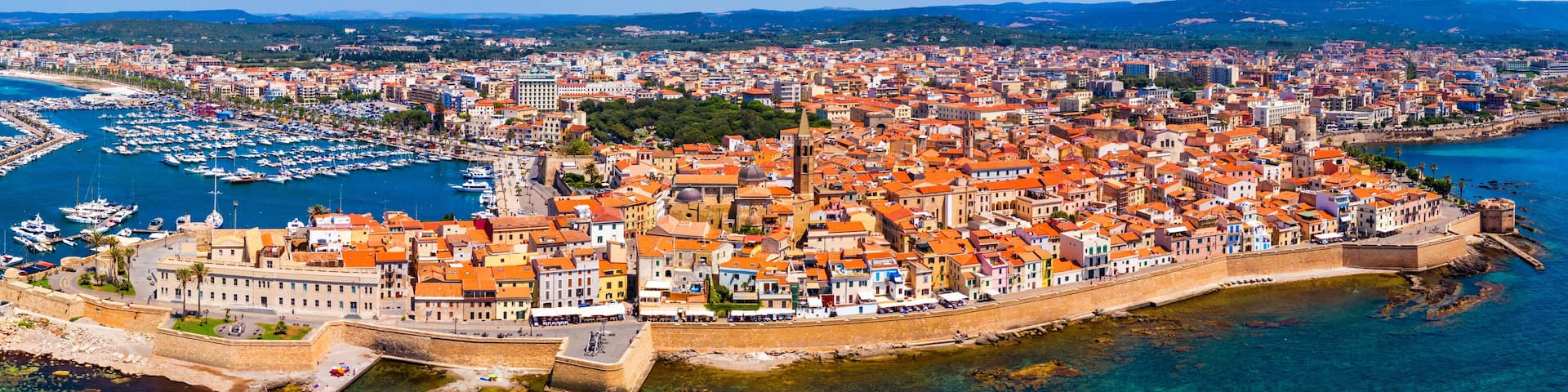 Aerial view over Alghero old town, cityscape Alghero view on a beautiful day with harbor and open sea in view. Alghero, Italy. Panoramic aerial view of Alghero, Sardinia, Italy.