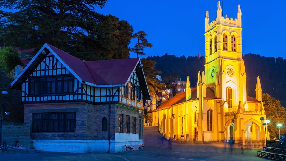A historic building with a red roof and a church with a clock tower.