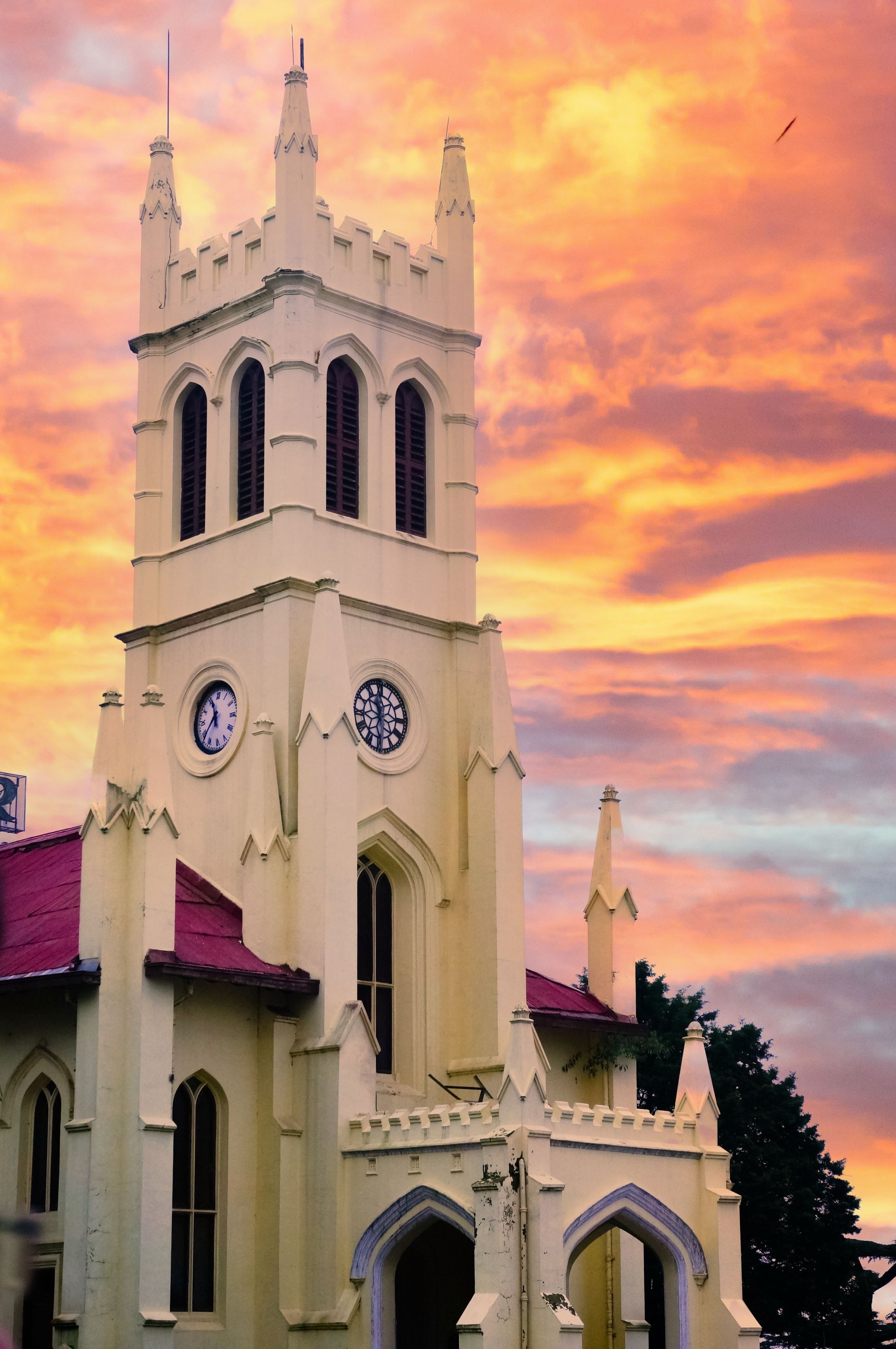 A church with a clock tower, arched windows, and a red roof.