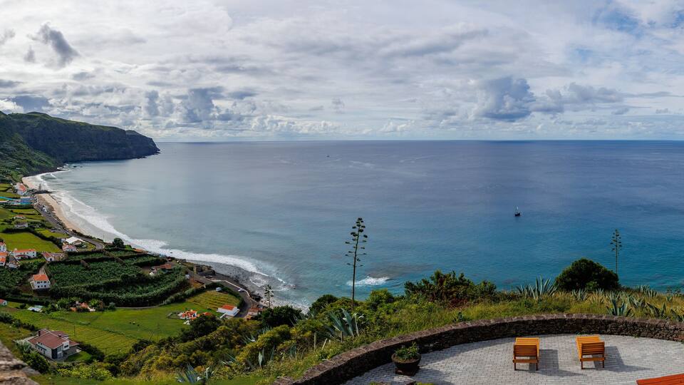 A coastal village with houses, a beach, and a view of the ocean.