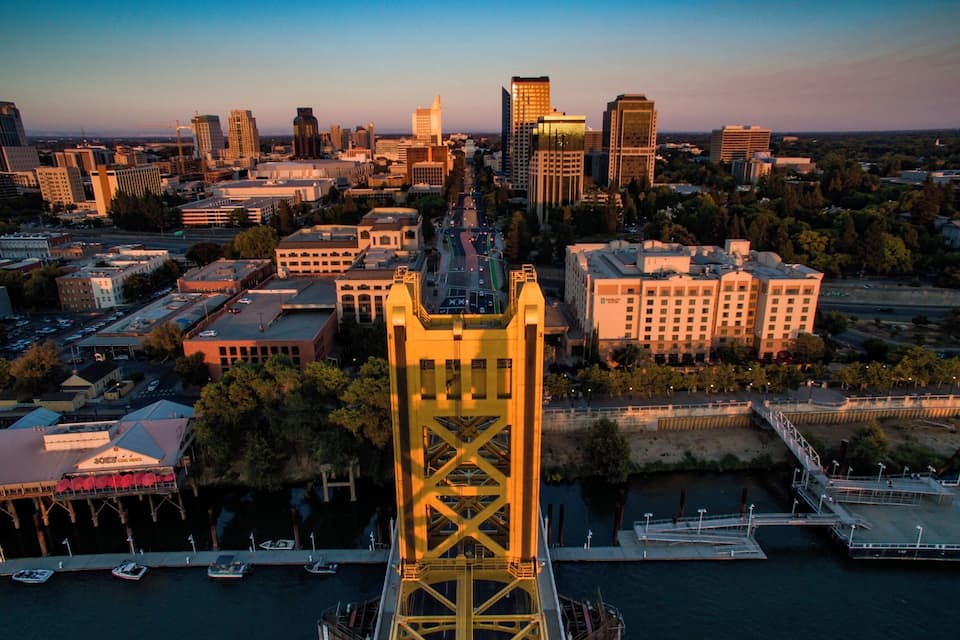 Un paisaje urbano con un puente amarillo destacado, edificios modernos y un río.