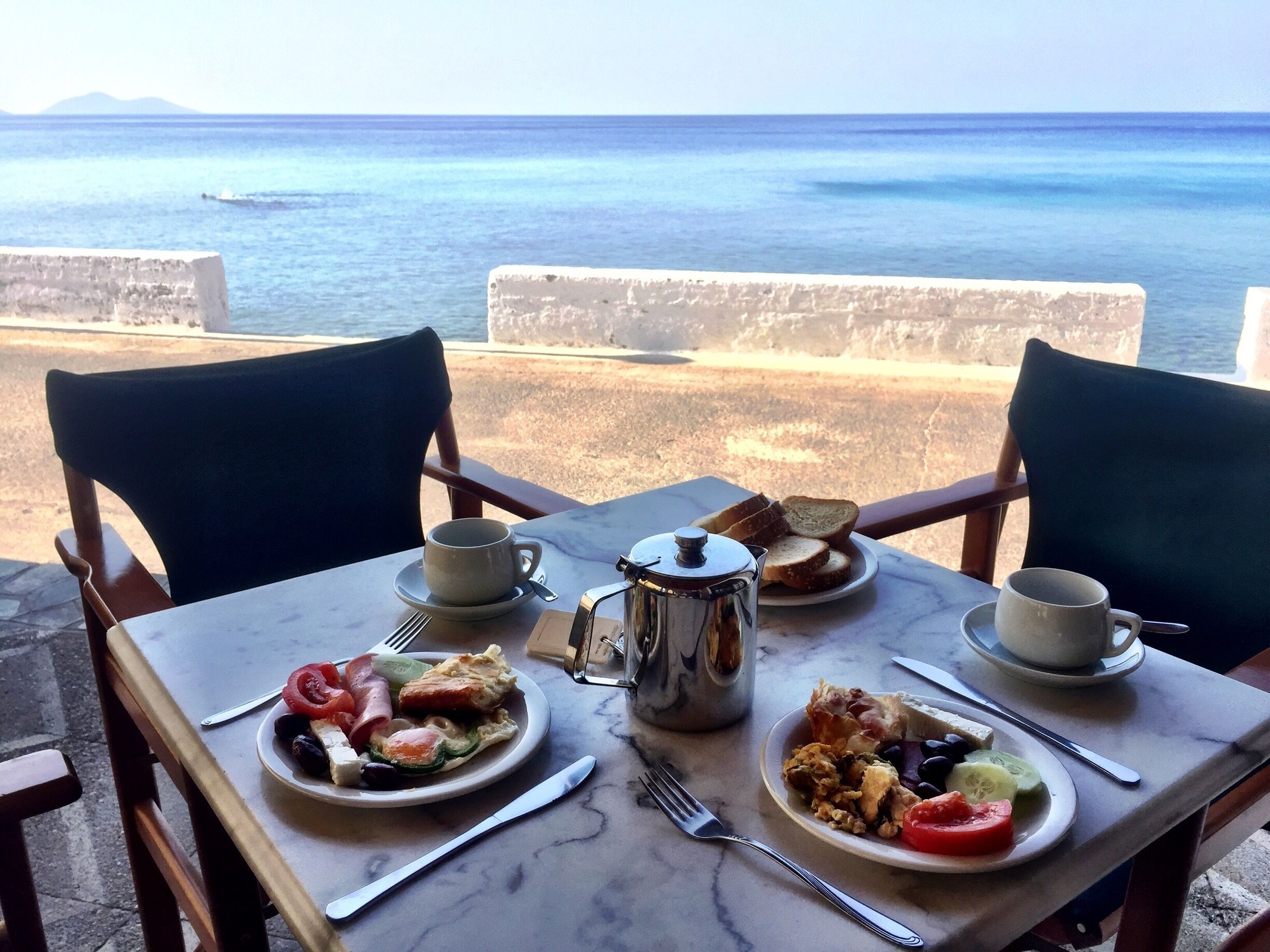 A table with breakfast items and a view of the sea.