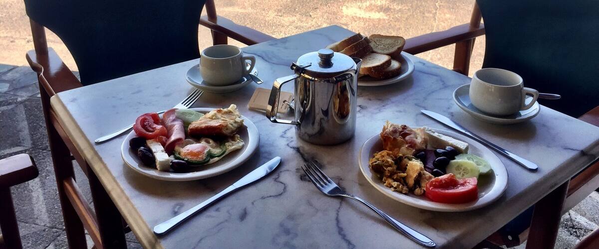 A table with breakfast items and a view of the sea.