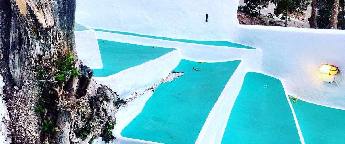 A white-walled pool with turquoise water, surrounded by a rocky landscape.