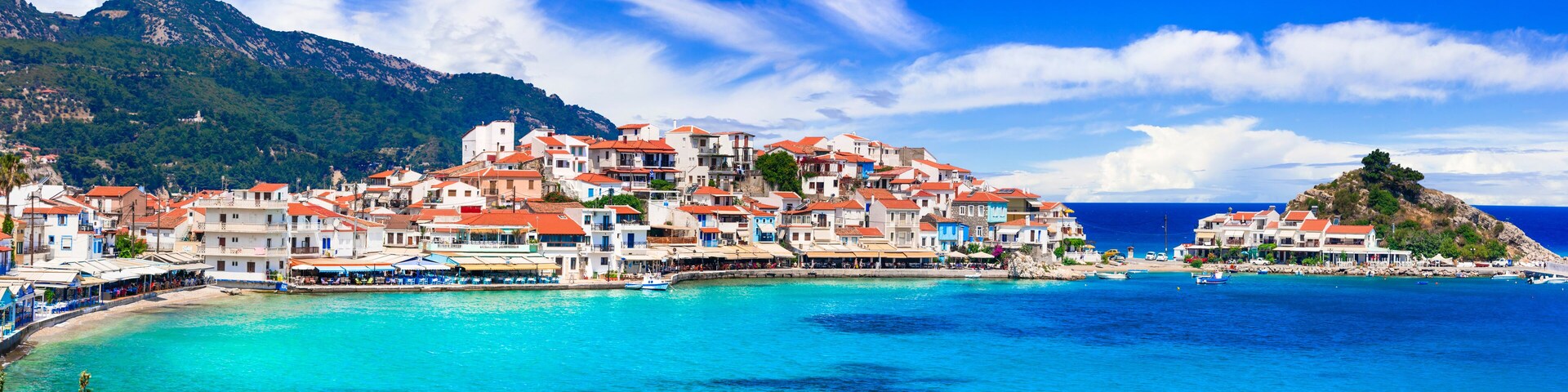 Un pueblo costero con edificios de colores y un mar azul cristalino.