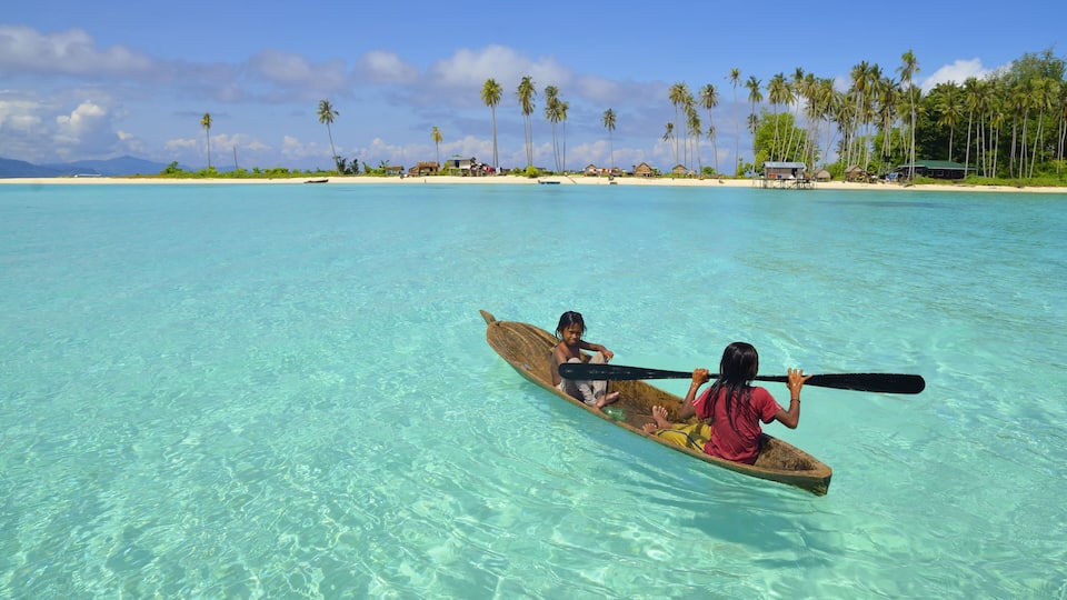 Background of seascape with children rowing boat on clear water, at Semporna, Sabah in Malaysia
