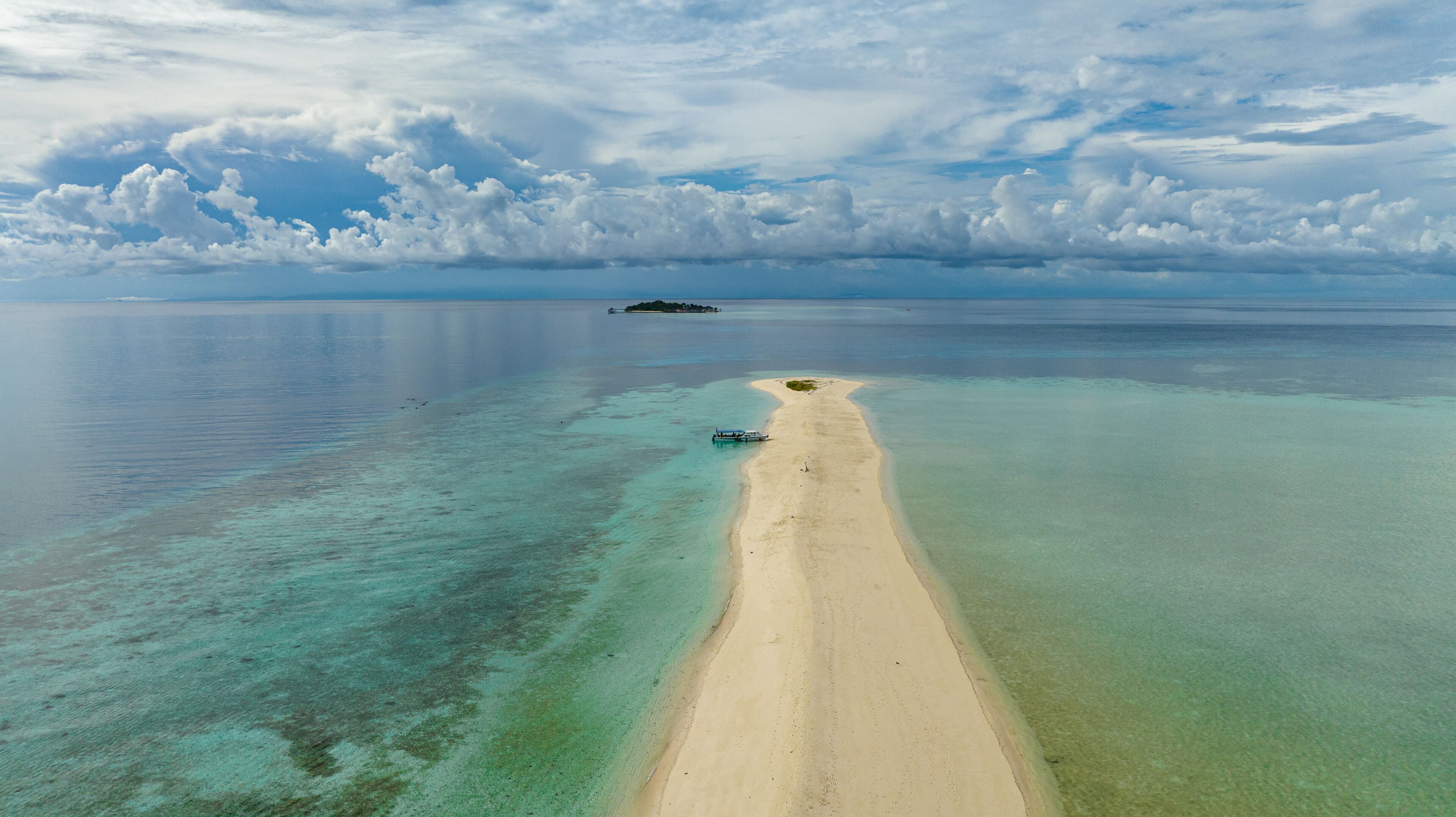 A tropical beach with clear turquoise waters, a sandy shore, and a small island in the distance.