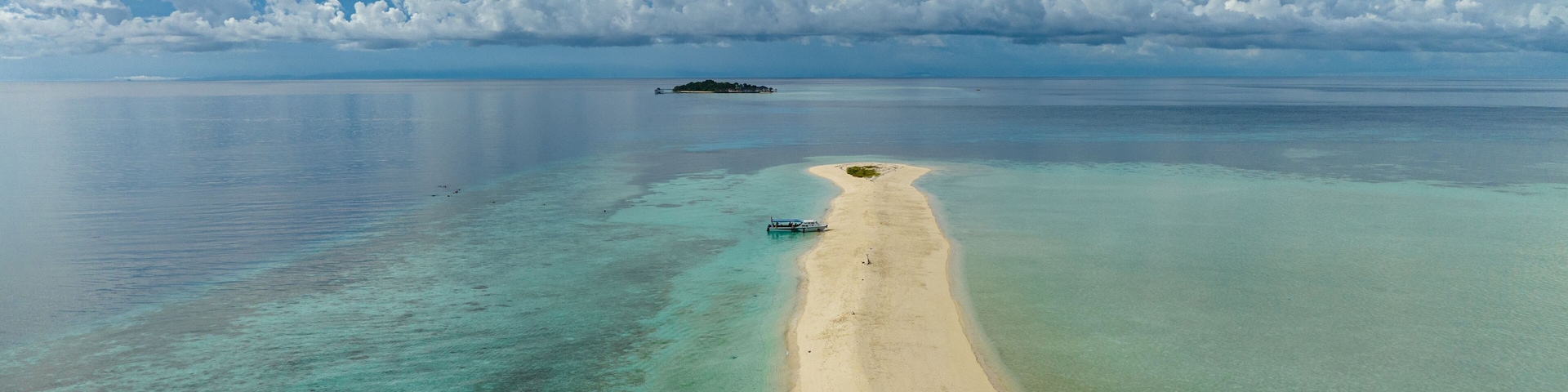 A tropical beach with clear turquoise waters, a sandy shore, and a small island in the distance.