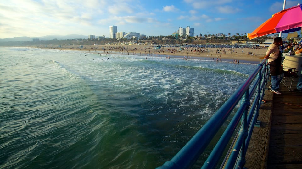 A beach with waves, a pier, and a city skyline in the background.