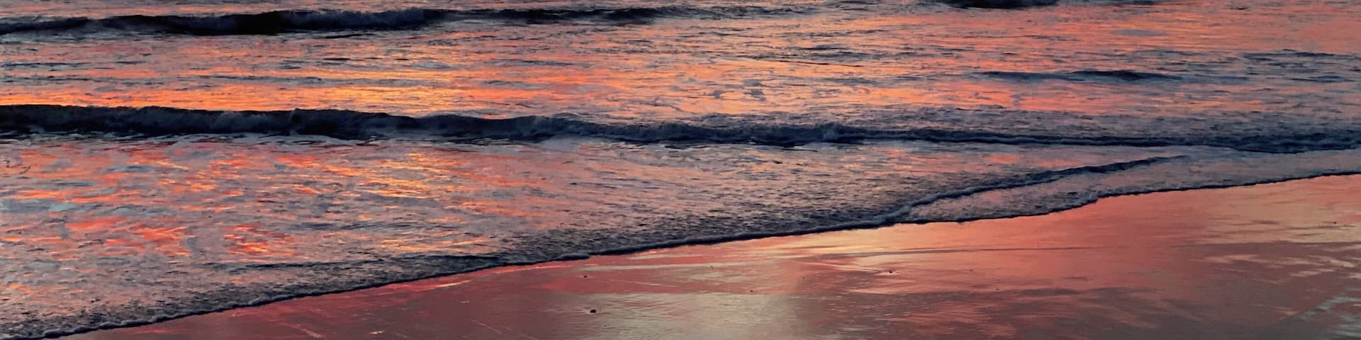 A beach with waves at sunset.