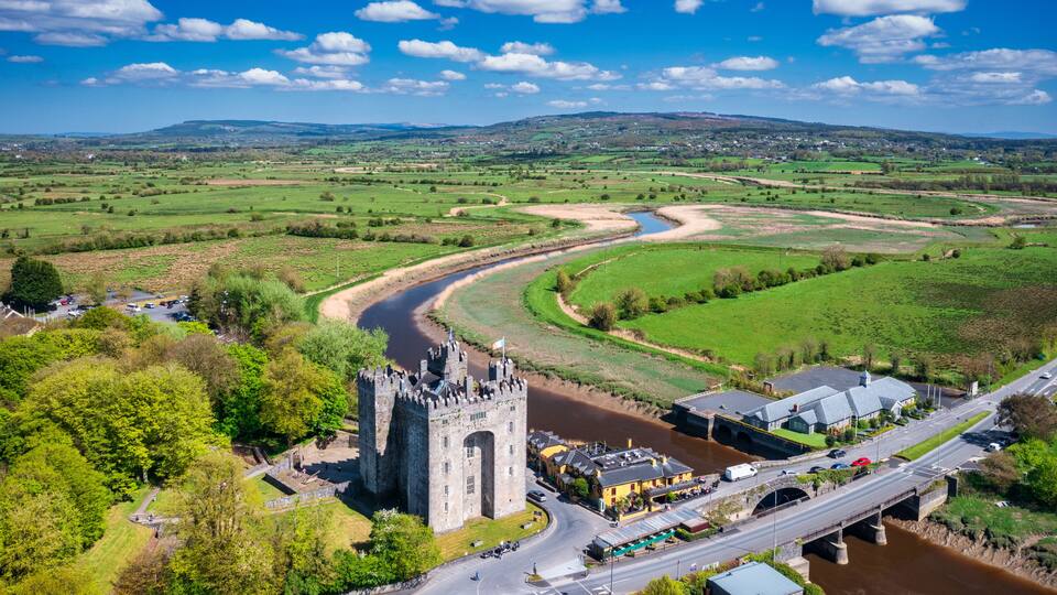 A castle, a river, and a bridge in a rural landscape.
